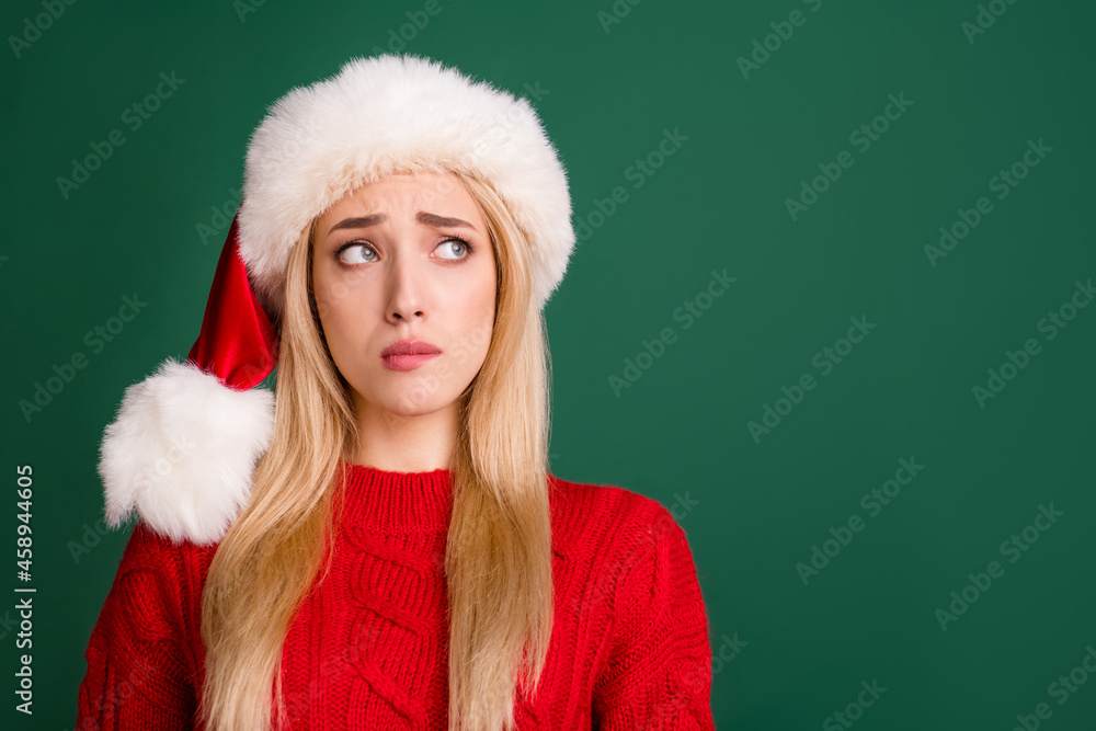 Photo of unhappy young upset doubtful woman look empty space christmas season isolated on green color background Photo of unhappy young upset doubtful woman look empty space christmas season isolated on green color background