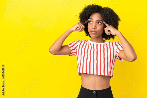 Young African American woman isolated on yellow background having doubts and thinking