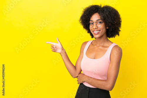 Young African American woman isolated on yellow background pointing finger to the side