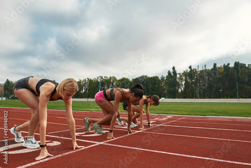 Professional female runners ready to start race on track field at stadium