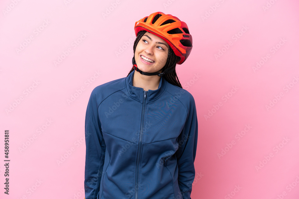 Teenager cyclist girl isolated on pink background looking to the side and smiling Teenager cyclist girl isolated on pink background looking to the side and smiling