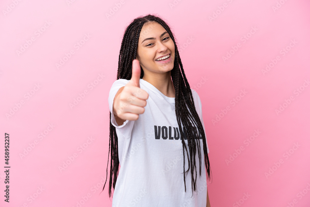 Teenager volunteer girl with braids isolated on pink background with thumbs up because something good has happened Teenager volunteer girl with braids isolated on pink background with thumbs up because something good has happened