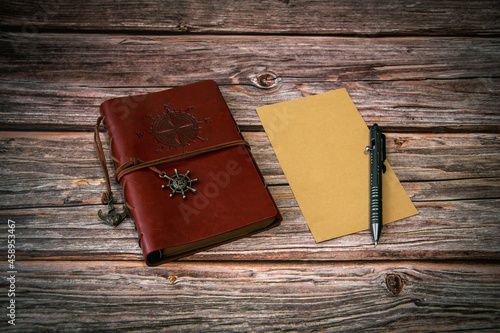 A notebook and a pen are lying on a wooden background