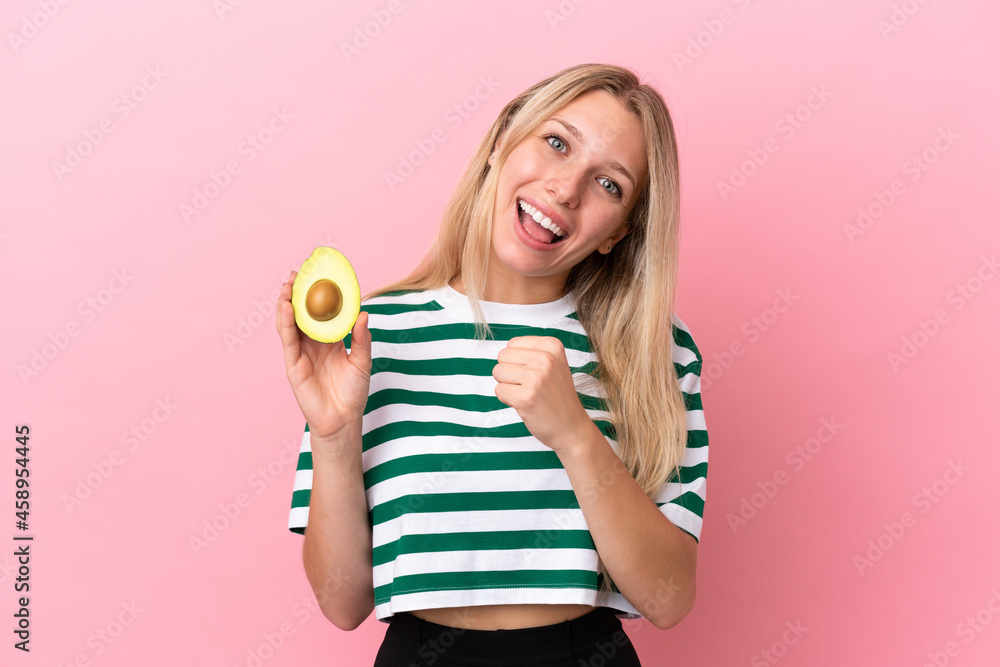 Young caucasian woman holding an avocado isolated on pink background celebrating a victory Young caucasian woman holding an avocado isolated on pink background celebrating a victory