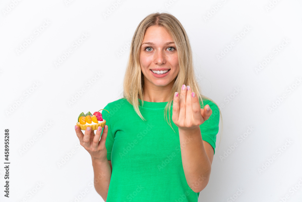 Young caucasian woman holding a tartlet isolated on white background inviting to come with hand. Happy that you came Young caucasian woman holding a tartlet isolated on white background inviting to come with hand. Happy that you came