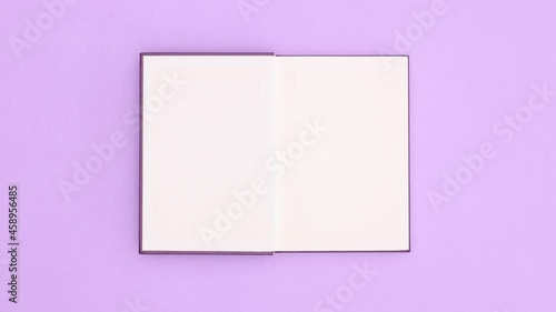 Dark purple hardcover book appear on purple background and open. Stop motion