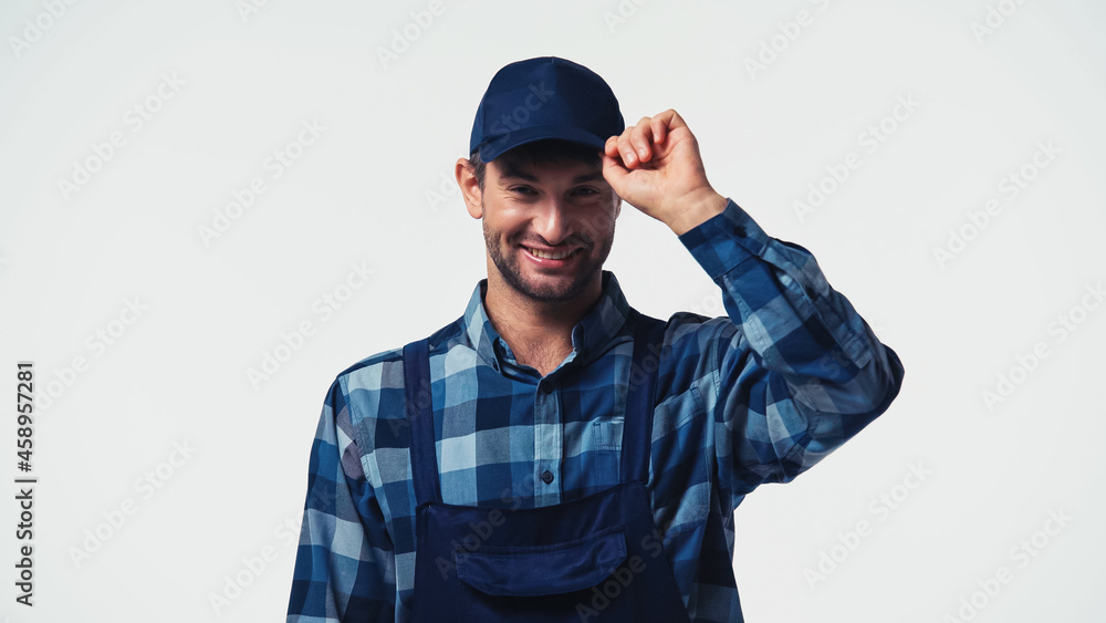 Happy workman adjusting cap and looking at camera isolated on white Happy workman adjusting cap and looking at camera isolated on white