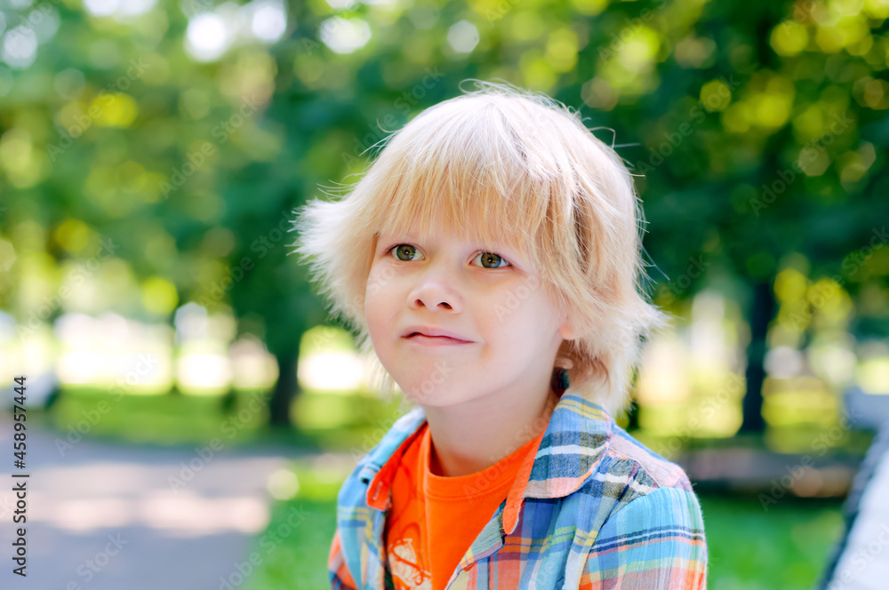 Cute blonde caucasian kid sitting on the bench at the park. Summer vacation happy childhood Cute blonde caucasian kid sitting on the bench at the park. Summer vacation happy childhood