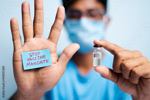 Focus on hands, Young man with medical face mask showing stop vaccine mandate - concept vaccine hesitancy.