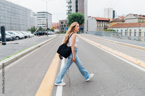 Young long blonde hair caucasian woman walking outdoor commuting going to work or strolling enjoying city living