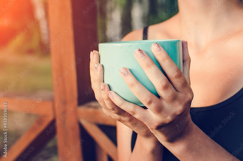 A girl holds a cup of tea in her hands on a background of autumn nature. Autumn concept. A girl holds a cup of tea in her hands on a background of autumn nature. Autumn concept.