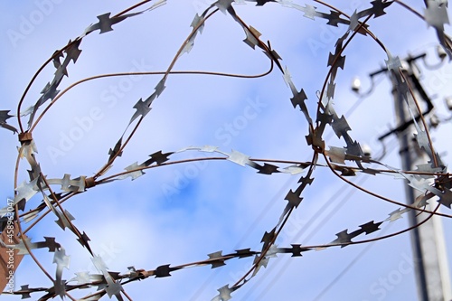 The fence is made of barbed wire. Barbed wire, the sky in the clouds. Fencing to protect the territory. Detention in prison.