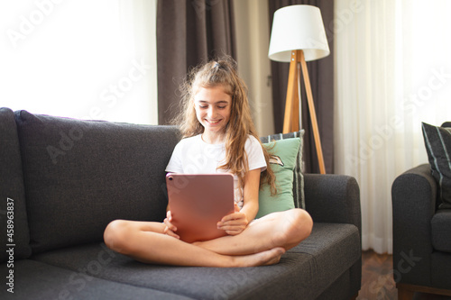 Portrait of a happy teenage girl using digital tablet in home.	