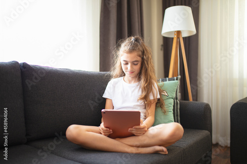 Portrait of a happy teenage girl using digital tablet in home.	