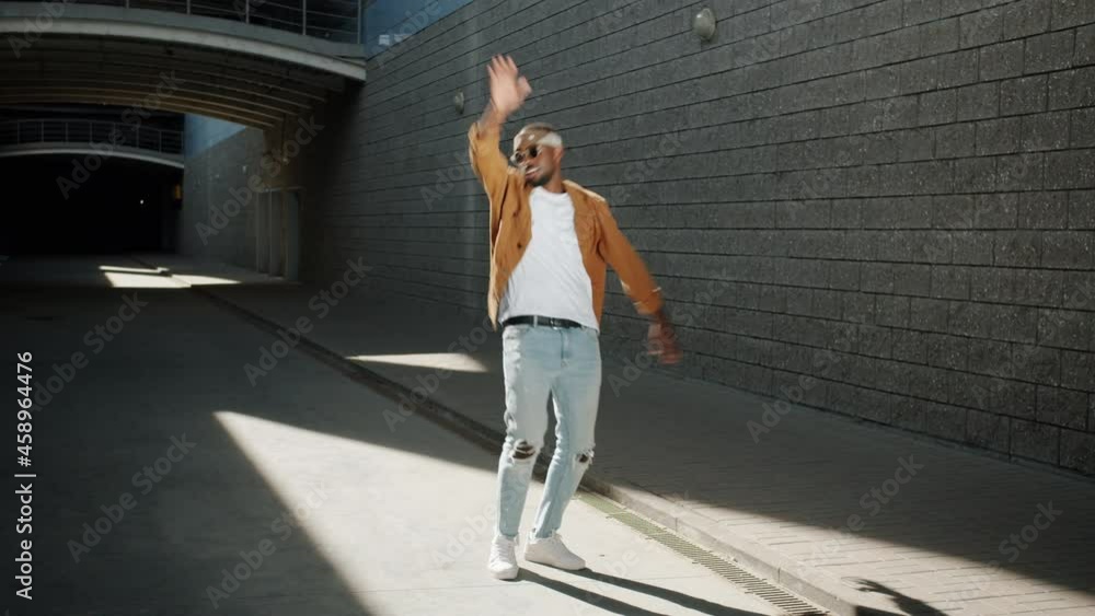 Happy African American man is having fun fooling around outdoors in urban street on sunny summer day. People and positive emotions concept. Happy African American man is having fun fooling around outdoors in urban street on sunny summer day. People and positive emotions concept.