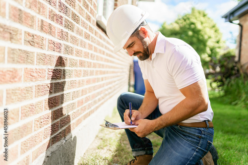 Obraz na płótnie man with a white hard hat holding a clipboard, inspect house
