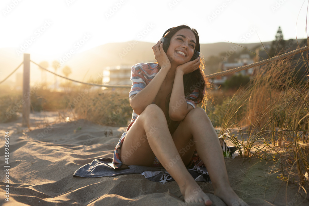 Happy young woman relaxing on the sandy beach. Beautiful woman listening the music... Happy young woman relaxing on the sandy beach. Beautiful woman listening the music...