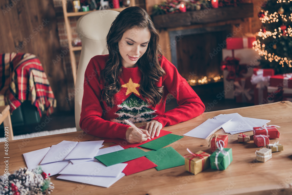 Fototapeta premium Photo of sweet pretty young woman dressed print pullover smiling writing christmas wishes indoors room home house