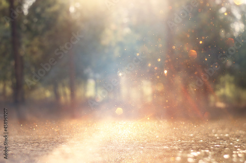 blurred abstract photo of light burst among lonely tree and glitter golden bokeh lights