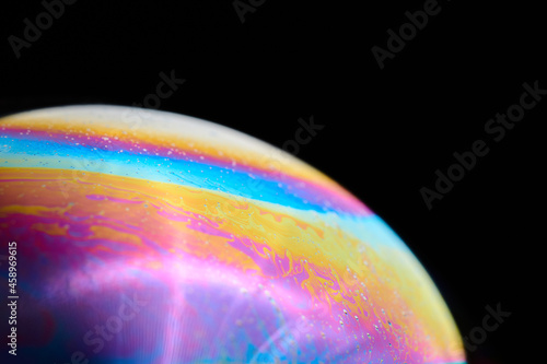Rainbow macro photography of a soap bubble, groovy colorful and abstract wallpaper or background of sphere. Beautiful planet or nebula with vibrant colors