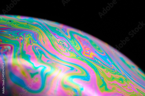 Rainbow macro photography of a soap bubble, groovy colorful and abstract wallpaper or background of sphere. Beautiful planet or nebula with vibrant colors