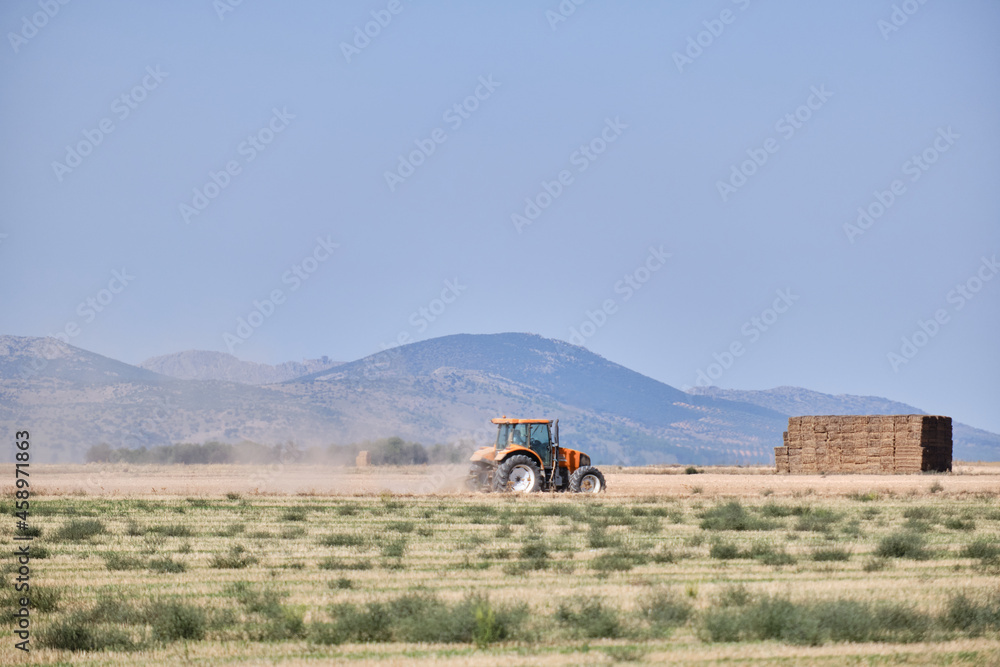 Obraz premium Tractor working in the harvest on a summer day in Castilla la Mancha