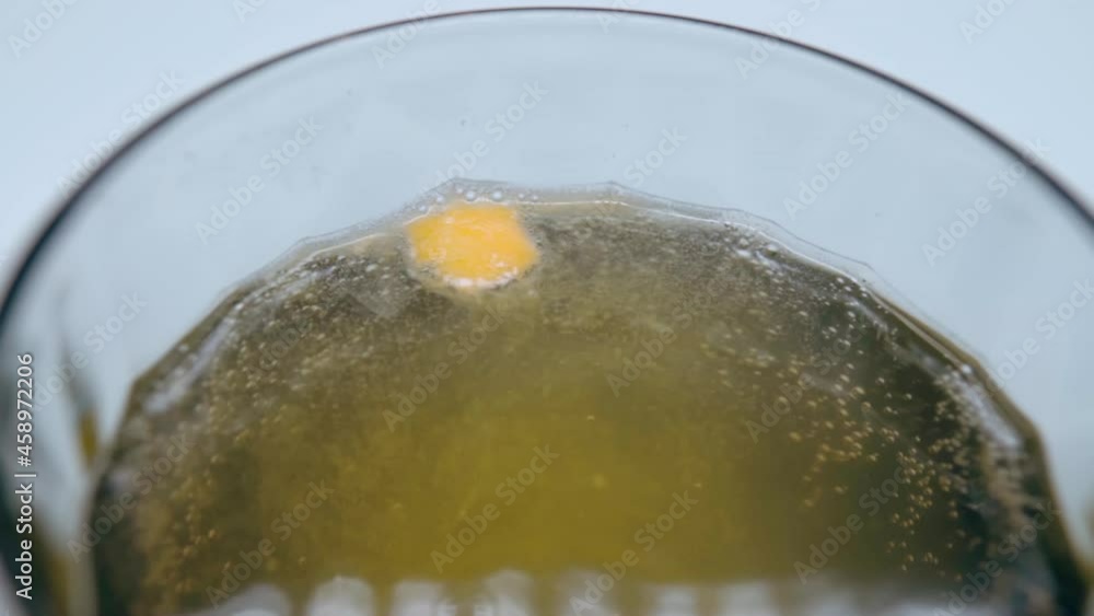 Small round orange effervescent tablet dissolving in water making bubbles, vitamin pills used for raising the human immune system of both healthy and sick person. Vitamin complex for improving health Small round orange effervescent tablet dissolving in water making bubbles, vitamin pills used for raising the human immune system of both healthy and sick person. Vitamin complex for improving health