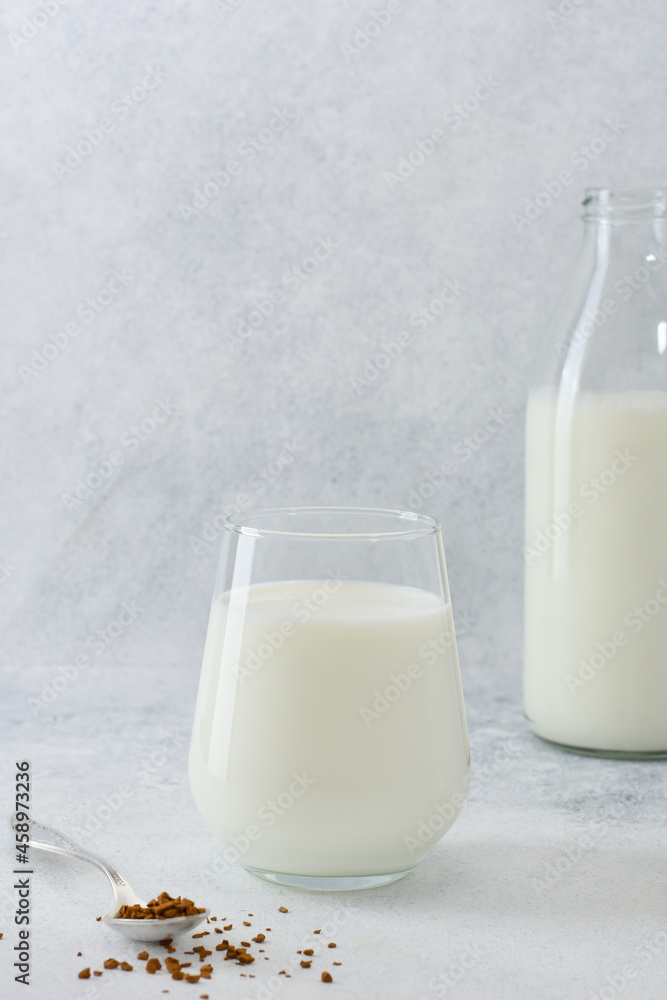 Ingredients to making coffee with milk. Instant coffee in spoon, a glass of milk and a bottle with milk on light grey background with copy space. Ingredients to making coffee with milk. Instant coffee in spoon, a glass of milk and a bottle with milk on light grey background with copy space.