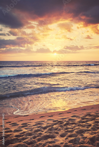 Tropical sandy beach with footprints in the sand at sunset, color toning applied, Sri Lanka.