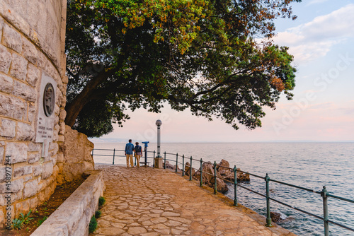 Opatija, Croatia - June 4, 2019: senior couple walking by city quay photo