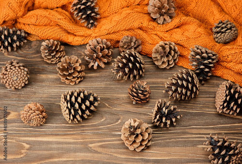 Autumn background. Orange plaid with pine cones on a wooden background. Autumn background. Orange plaid with pine cones on a wooden background.