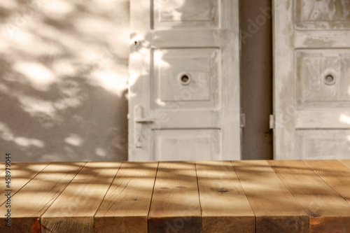Wooden table with a natural minimalist shade on the wall at sunset 