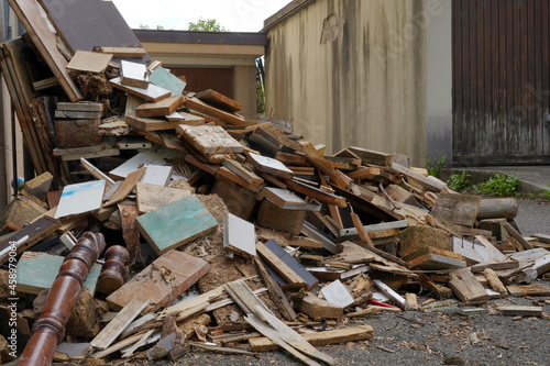 Dismantled furniture on a yard between two buildings. There are pieces of wooden furniture piled up. They are of irregular size. It looks like vacating of a dwelling.