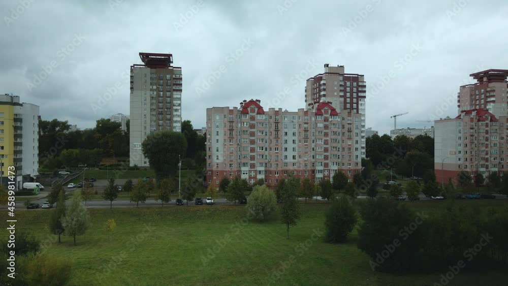 Flight over the city block in cloudy weather. Multi-storey buildings and trees with yellowed leaves in the suburbs. Gray sky shaded by clouds. Aerial photography. Flight over the city block in cloudy weather. Multi-storey buildings and trees with yellowed leaves in the suburbs. Gray sky shaded by clouds. Aerial photography.