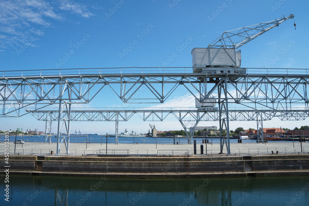 Port container gantry crane in Copenhagen, Denmark. Full-slewing jib crane, the slewing part of which is installed on a gantry moving on rails laid on the ground or overpass.