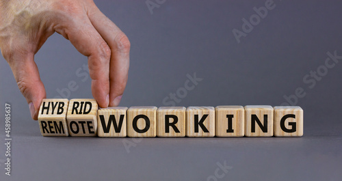 Hybrid or remote working symbol. Businessman turns cubes and changes words 'remote working' to 'hybrid working'. Beautiful grey background. Business, hybrid or remote working concept, copy space. photo