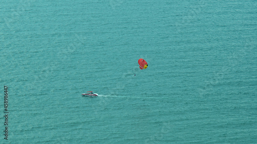 A parachutist above the sea surface flies behind a boat on a summer day, summer active recreation at the sea