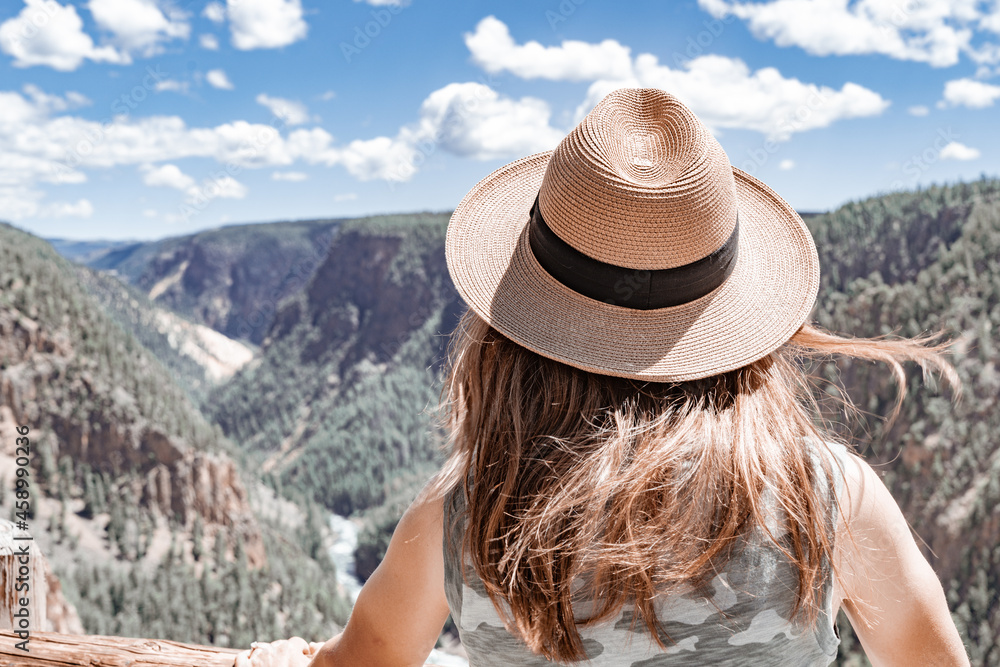 Woman wearing a hat enjoys the view of the Grand Canyon of Yellowstone National Park