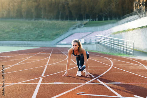 Female athlete starting her sprint on a running track. Runner taking off from the starting blocks on running track. Jogger activity. Female athlete. Sportswoman. Cardio exercises. Workout concept