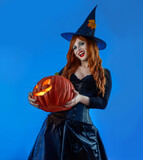 Halloween Witch Woman with long red hair and holiday make-up wearing dark tapered witch's hat
