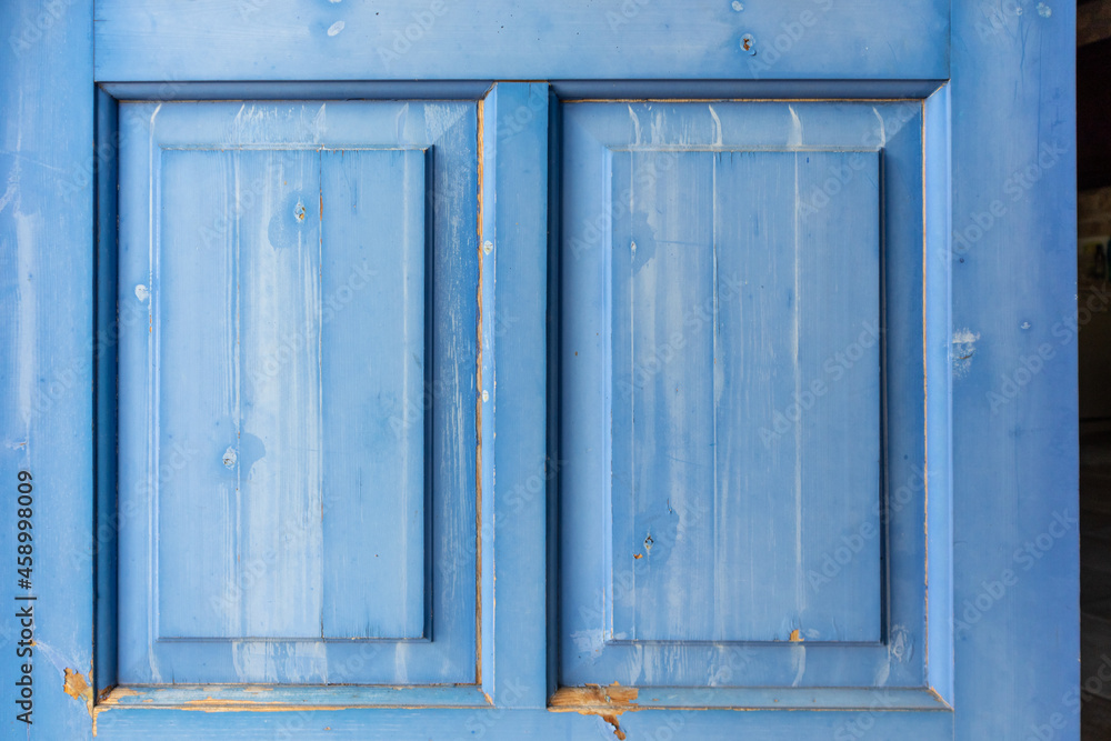 Entrance wooden closed door with blue shutters details close-up. Greek traditional house design elements. Summer travel locations architecture house elements
