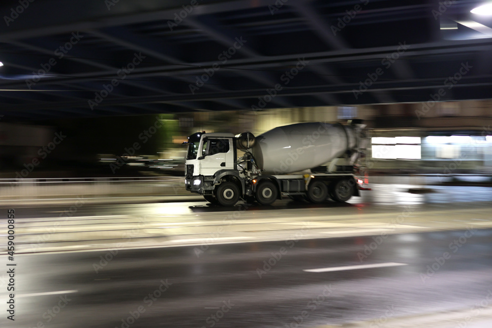 Duży samochód ciężarowy betoniarka w drodze na budowę nocą w mieście.  - obrazy, fototapety, plakaty 