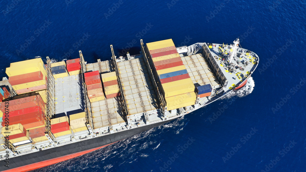 Fototapeta premium Aerial drone photo of colourful truck size container tanker ship cruising deep blue sea near commercial port of Piraeus, Attica, Greece