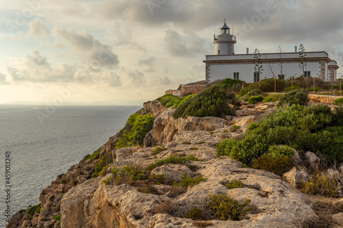 Cap Blanc lighthouse on the rocky coast of the island of Mallorca. In the background s seascape of the Mediterranean Sea at sunset with clouds. Sublime landscape © Nemesio
