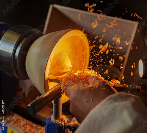 A wooden bowl being turned by a man on a woodturning lathe.A craftsman at work.Sawdust is flying.