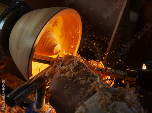 A wooden bowl being turned by a man on a woodturning lathe.A craftsman at work.Sawdust is flying.