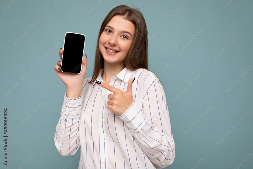 Photo of beautiful smiling young woman good looking wearing casual stylish outfit standing isolated on background with copy space holding smartphone showing phone in hand with empty screen display for Photo of beautiful smiling young woman good looking wearing casual stylish outfit standing isolated on background with copy space holding smartphone showing phone in hand with empty screen display for