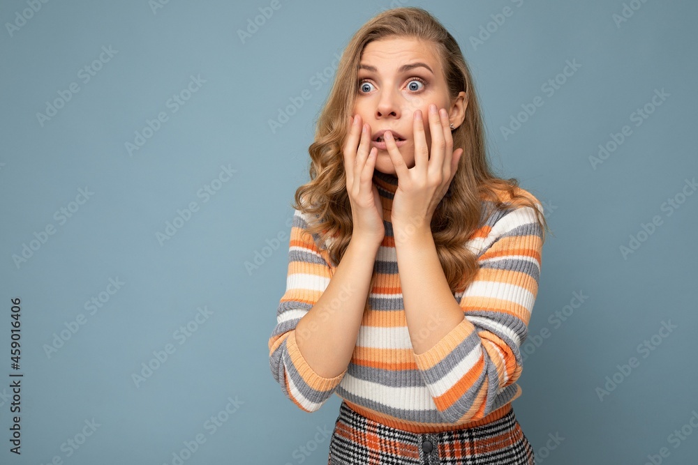 Young blond beautiful curly woman with sincere emotions wearing striped jersey isolated on blue background with empty space and covering eyes scared and woried female person Young blond beautiful curly woman with sincere emotions wearing striped jersey isolated on blue background with empty space and covering eyes scared and woried female person