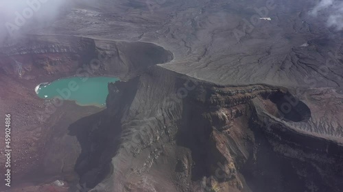 Crater with active volcano Goreliy smoke and clouds. Kamchatlka peninsula. Camera moving backward. 4K video. Aerial footage. photo