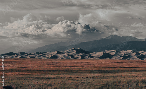 Beautiful view of Great Sand Dunes National Park in Colorado, with grassy plains, sand dunes, and Sangre de Cristo mountain range in the background